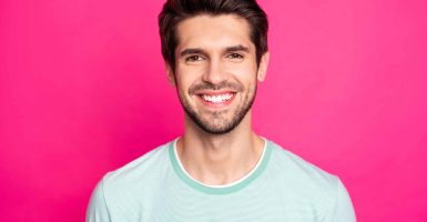 Close up photo of brunette amazing macho guy revealing perfect white teeth, wear casual t-shirt isolated vibrant pink color background